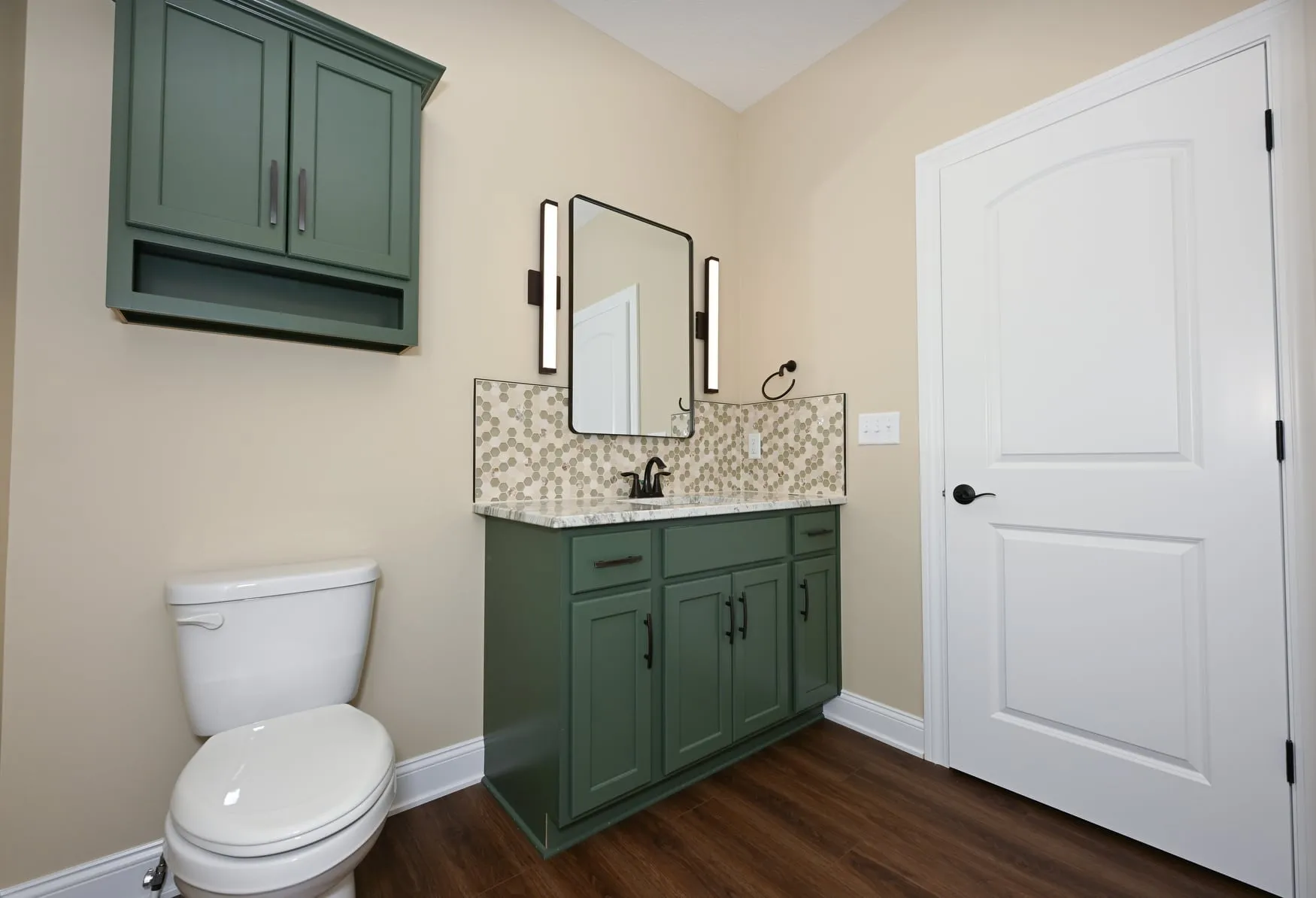 Bathroom with a green vanity and tiled backsplash