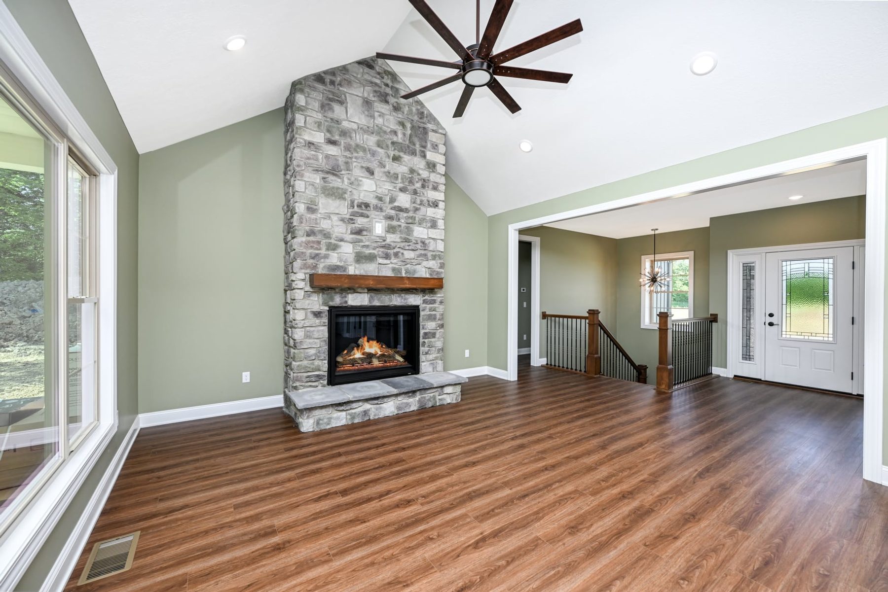 Vaulted great room with a stone fireplace open to the kitchen