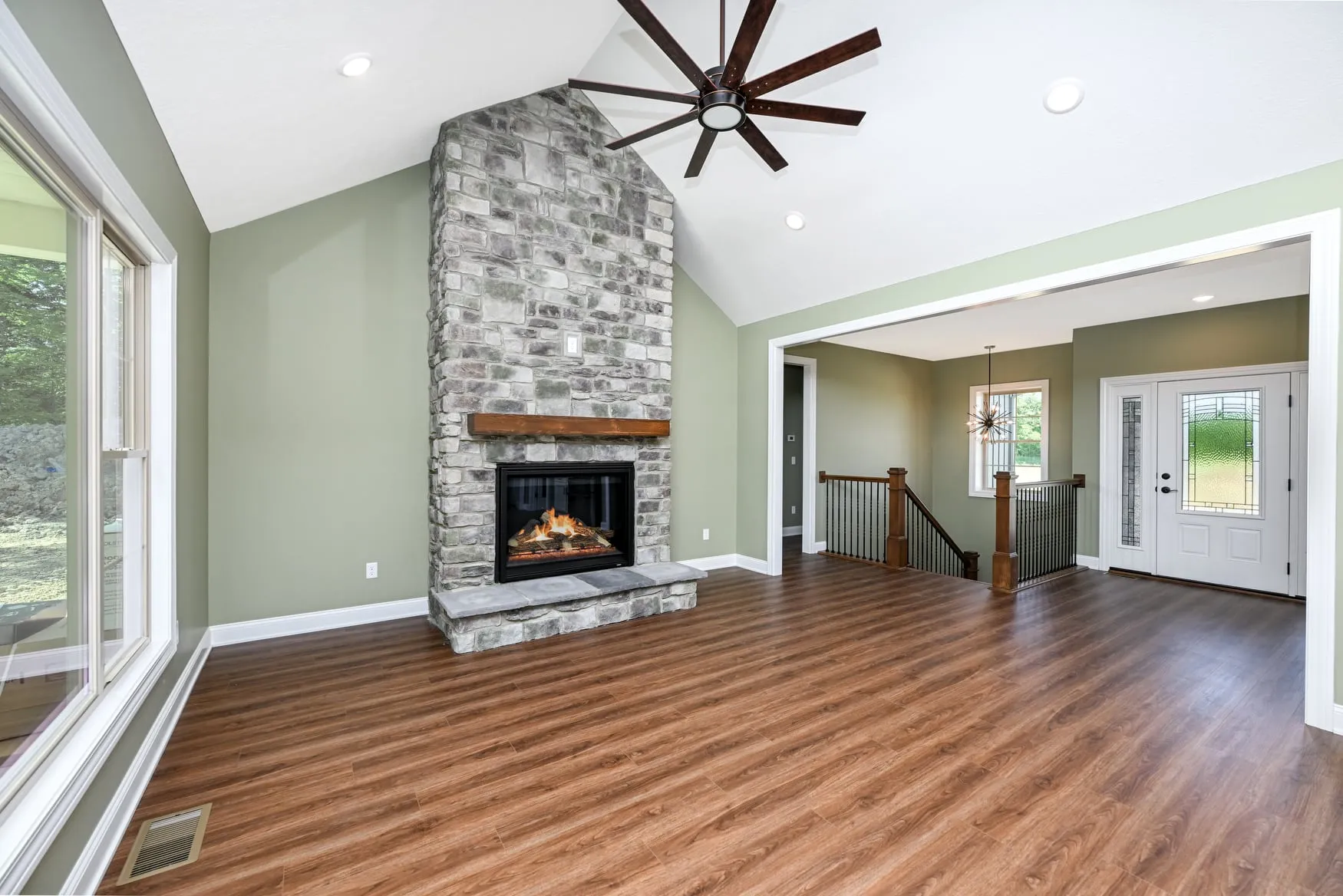 Vaulted great room with a stone fireplace open to the kitchen
