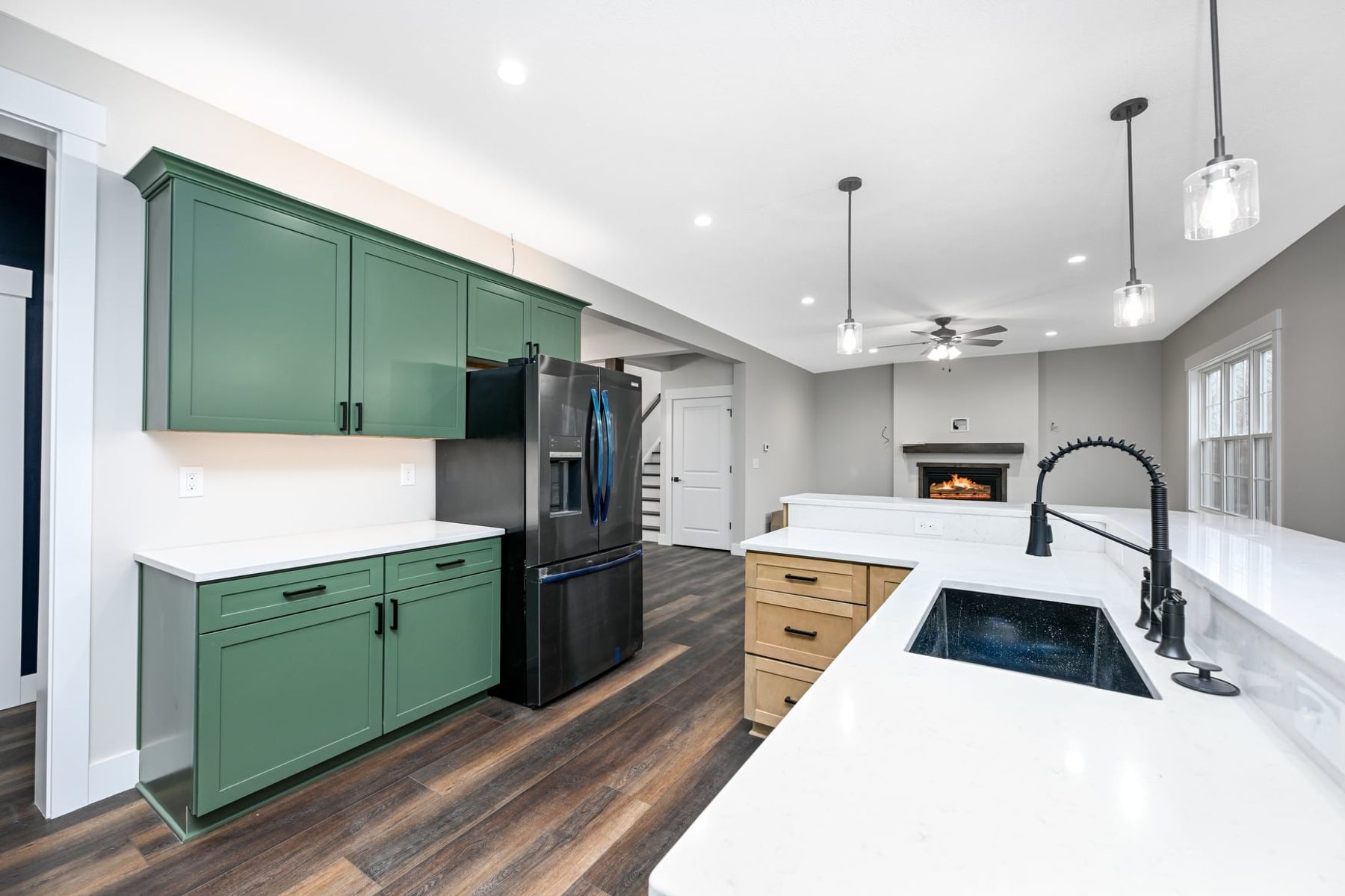 Green kitchen with a quartz island looking through to the fireplace