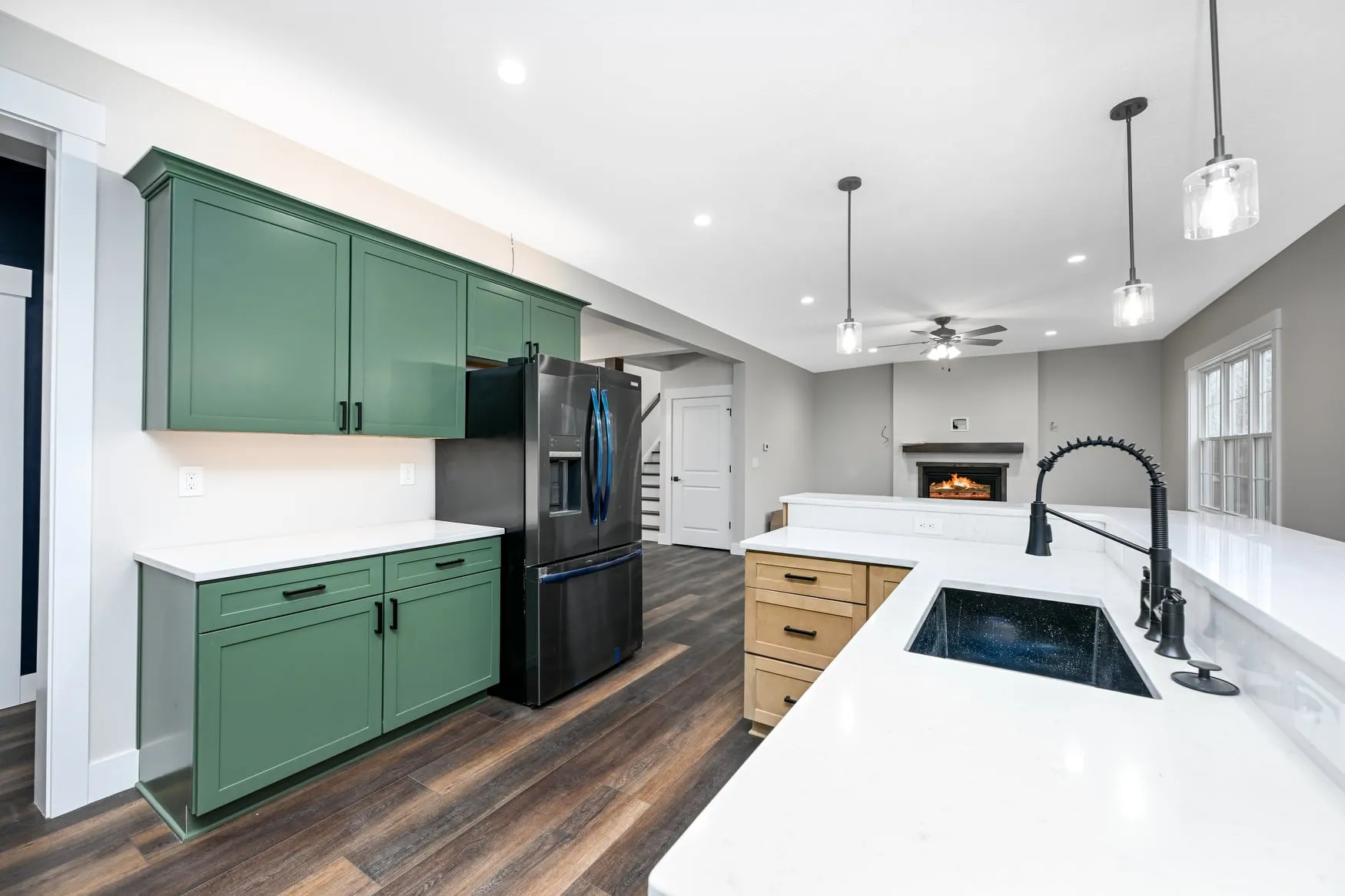Green kitchen with a quartz island, looking through to the fireplace