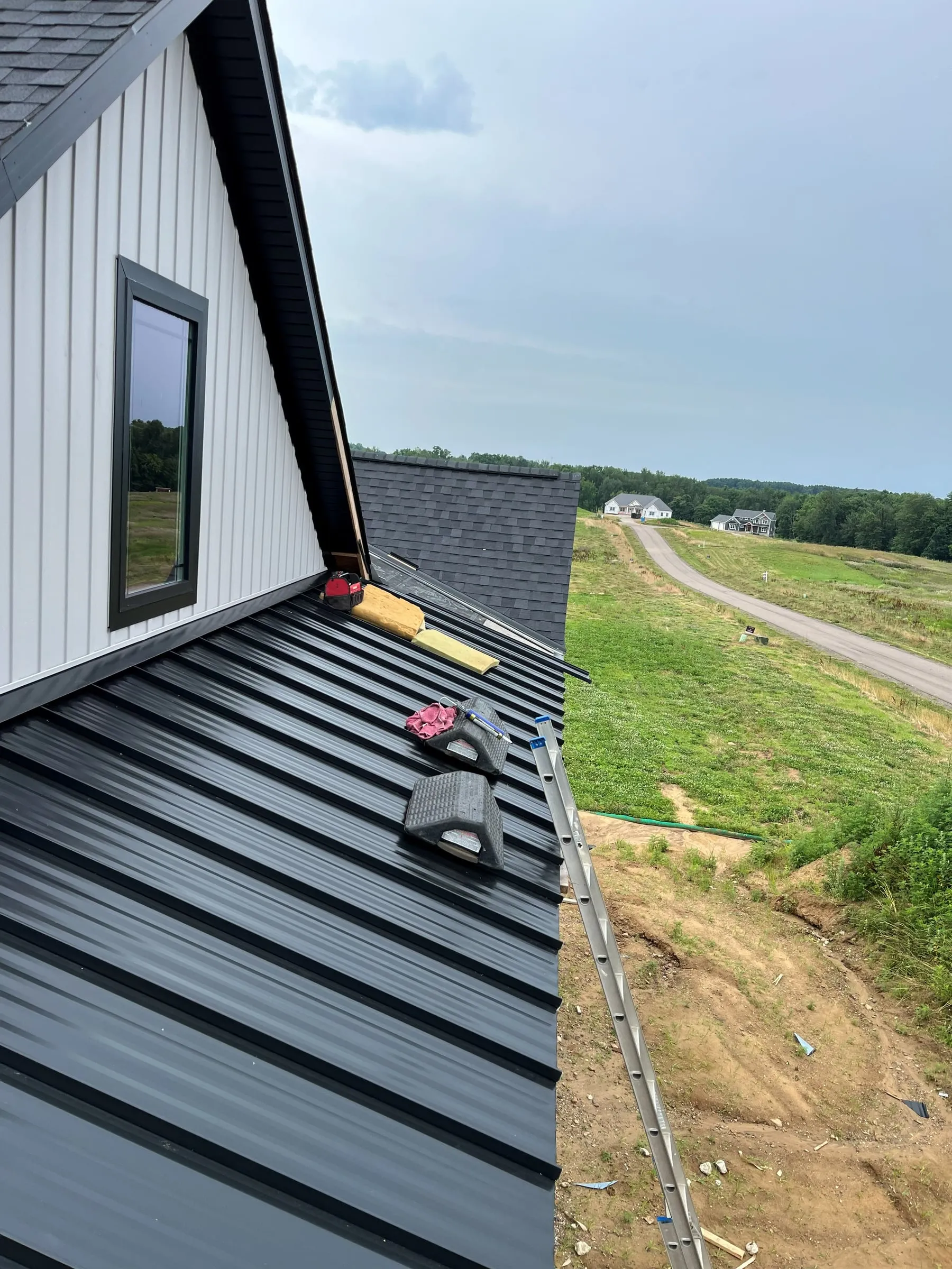 Standing-seam metal roof going on a new Hahn home, with other homes down the street