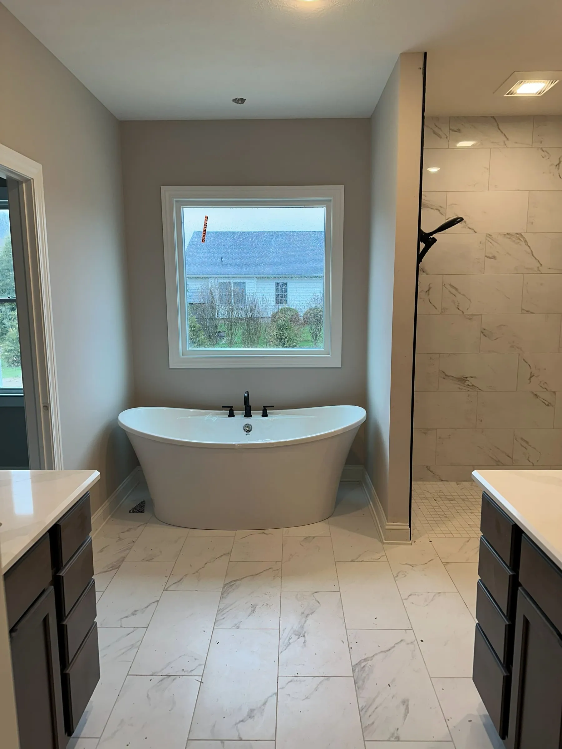 Owner's bath in the model home with a freestanding soaking tub and marble-tiled shower