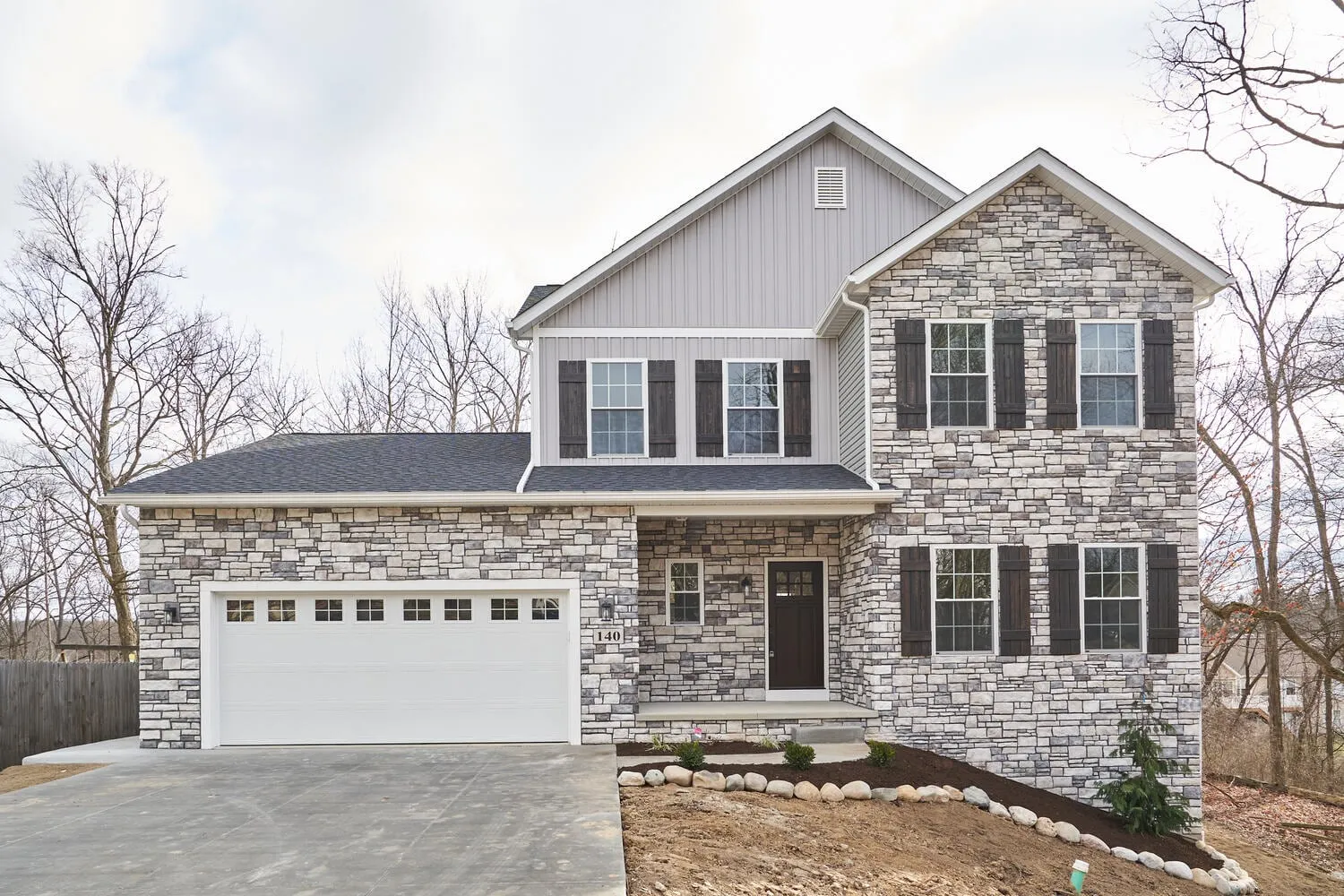 Two-story home with stone and gray siding